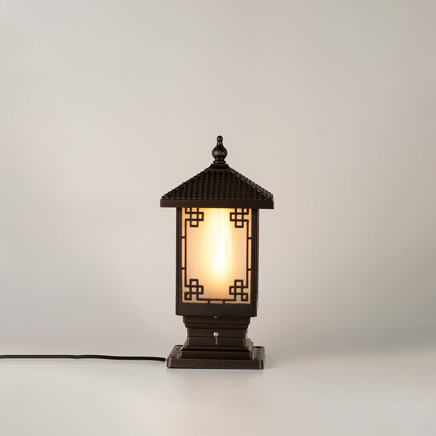 Vintage black outdoor gate light with warm glowing glass panels for elegant exterior decor use.