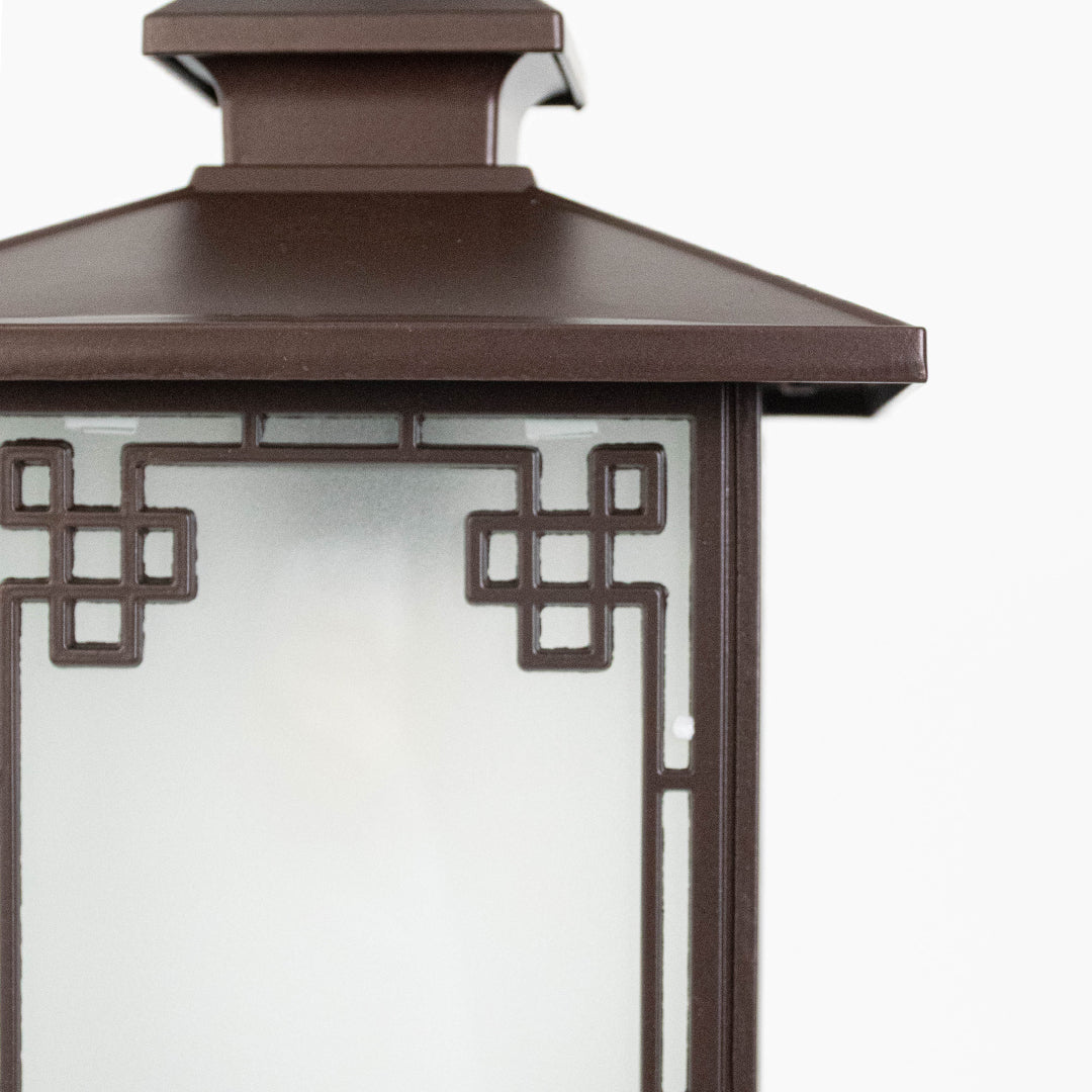 Closeup of brown metal outdoor lantern with geometric glass panels on white background ideal for gate entrance and exterior decor lighting.