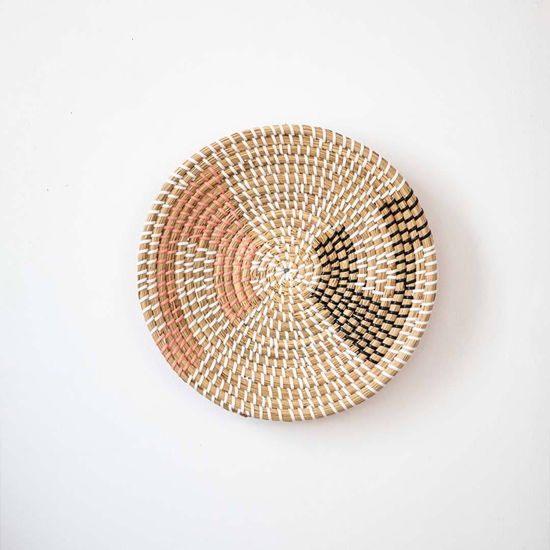 Minimalist woven seagrass wall basket plate featuring geometric orange and black accents isolated on a white backdrop.