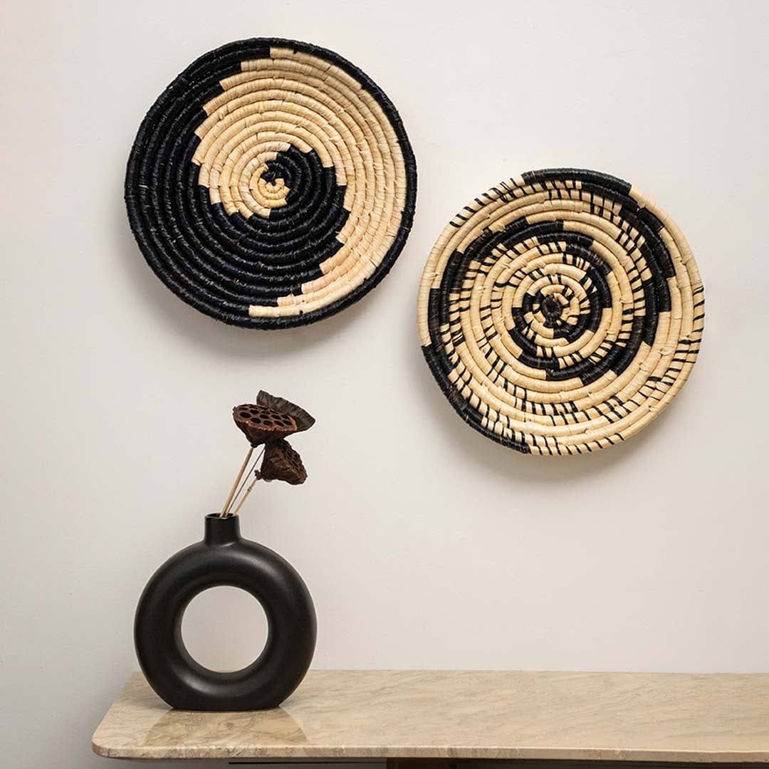 Handcrafted black cream seagrass wall basket set with modern spiral patterns displayed in bohemian lifestyle living room.