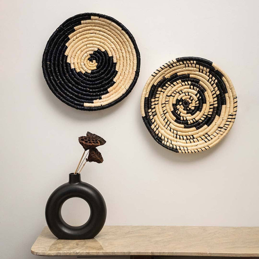 Handcrafted black cream seagrass wall basket set with modern spiral patterns displayed in bohemian lifestyle living room.