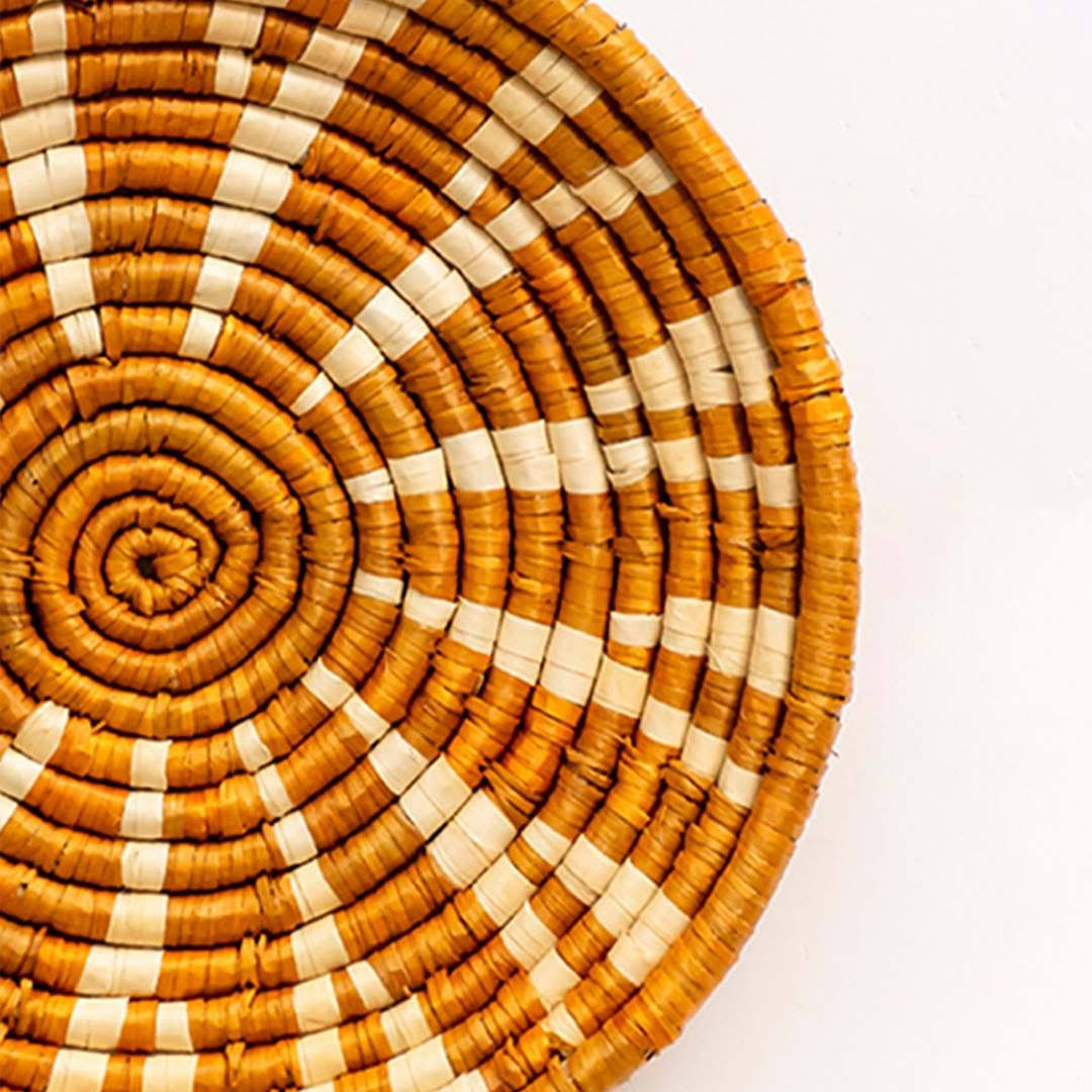 Handwoven seagrass wall basket decor showcasing intricate terracotta spiral weave and natural fiber artisan craftsmanship.