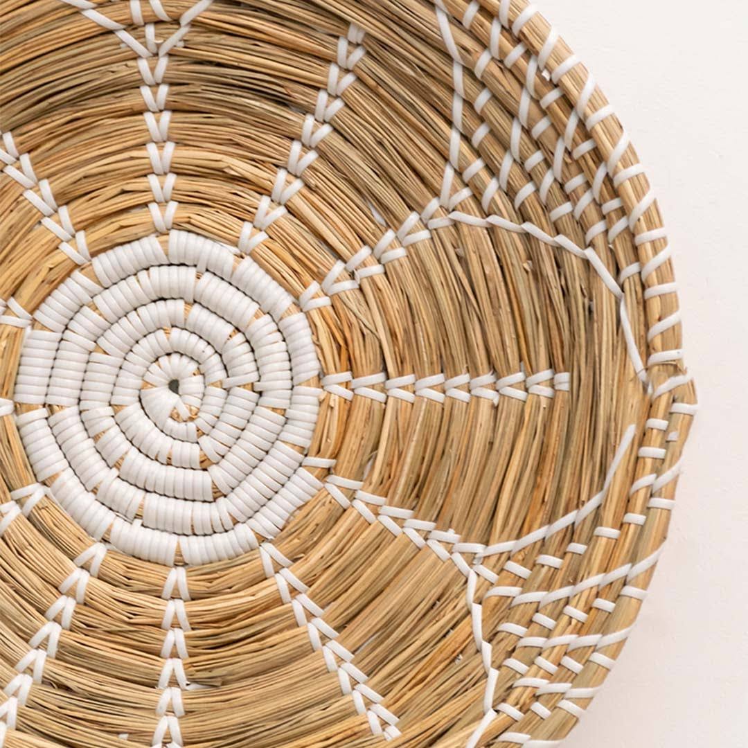 Handwoven seagrass wall basket decor showcasing intricate white spiral weave and natural fiber texture with artisan craftsmanship.