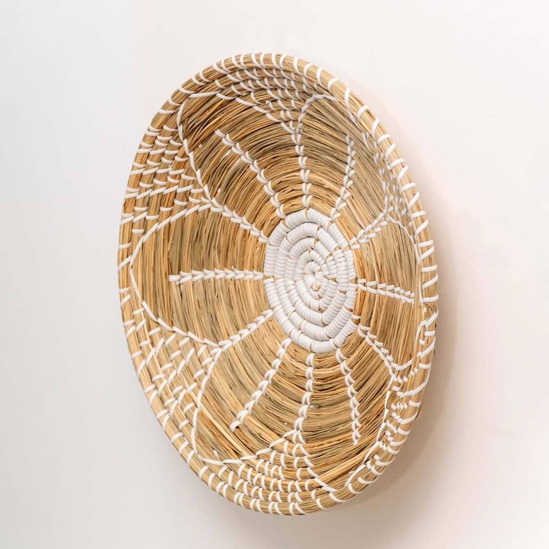 Handwoven seagrass round wall basket decor in natural beige with white spiral woven profile shown on white background.