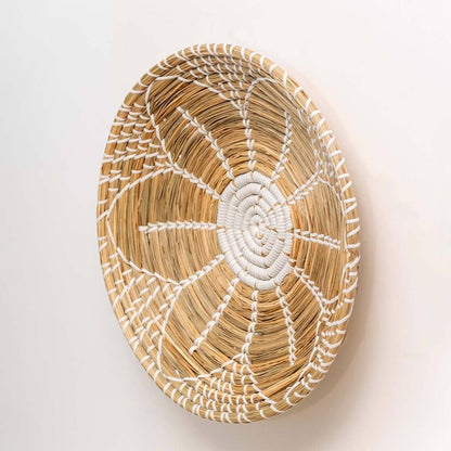 Handwoven seagrass round wall basket decor in natural beige with white spiral woven profile shown on white background.