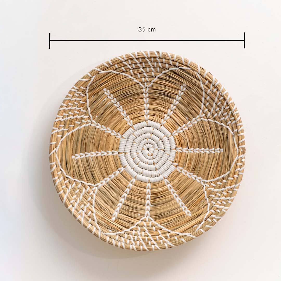 Handwoven seagrass round wall basket decor in natural beige with white spiral woven pattern and size guide on white.