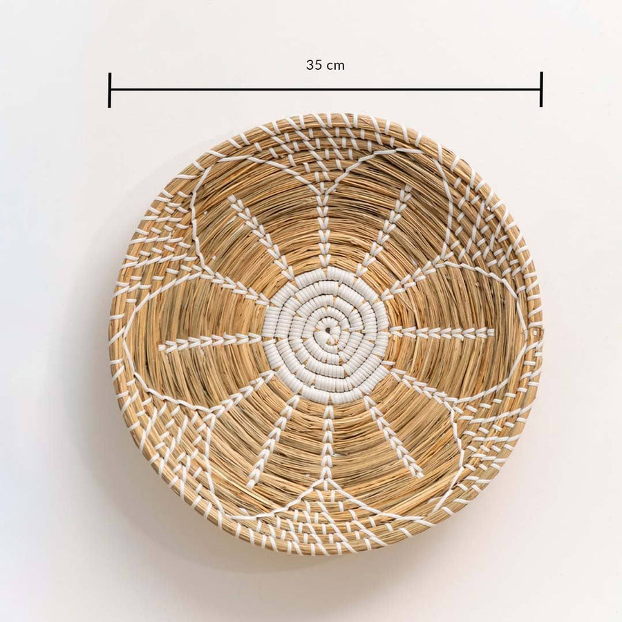 Handwoven seagrass round wall basket decor in natural beige with white spiral woven pattern and size guide on white.