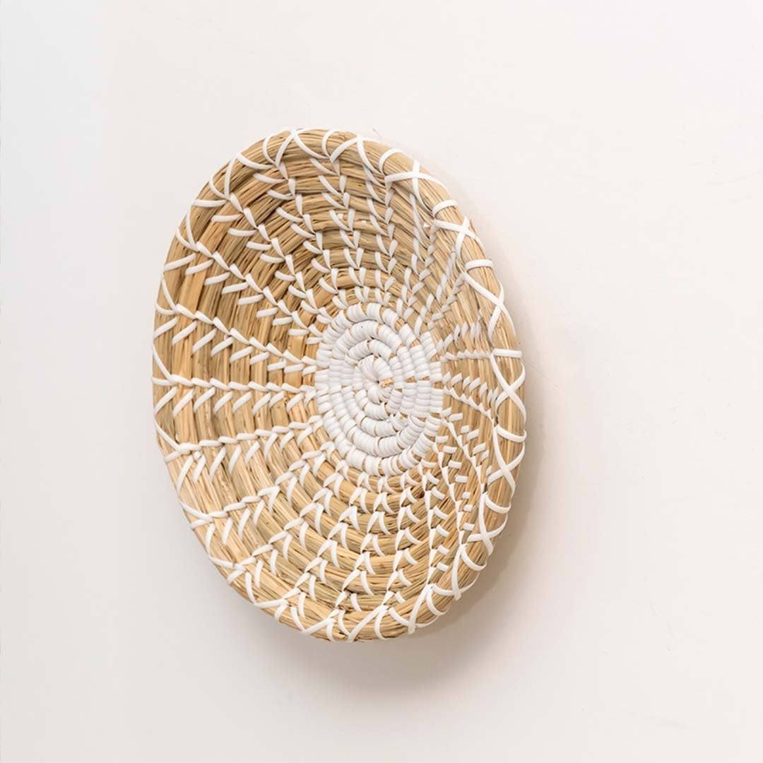 Handwoven seagrass round wall basket decor in natural beige with white spiral woven profile displayed on white background.