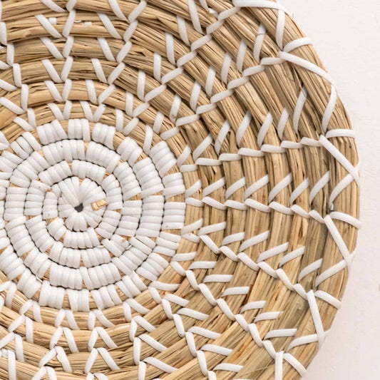 Handwoven seagrass wall basket decor highlighting intricate white spiral weave and natural fiber texture with artisan detail.