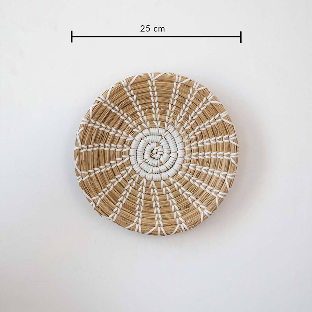 Handwoven seagrass round wall basket decor in natural beige with white radial woven pattern and size guide on white.
