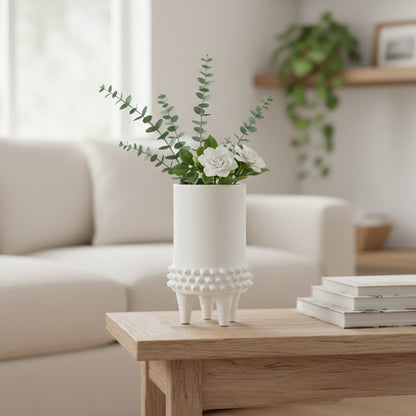 White ceramic floor vase with textured band and tripod legs placed in living room corner adding modern decorative elegance.