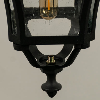 Closeup of black metal outdoor lantern with clear glass panels and bulb on white background perfect for exterior decor lighting.