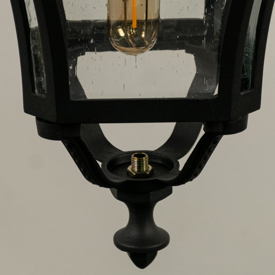 Closeup of black metal outdoor lantern with clear glass panels and bulb on white background perfect for exterior decor lighting.