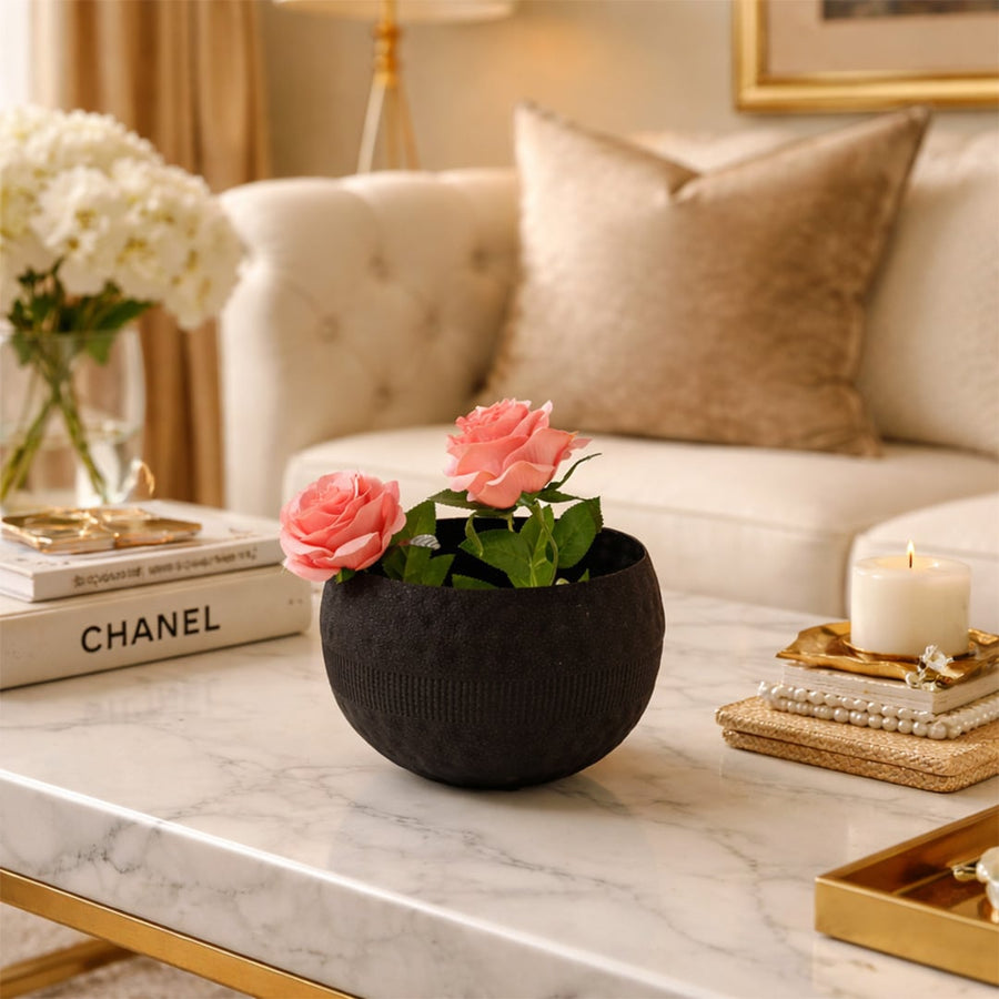 Textured black rounded metal bowl with pink flowers on marble table for luxury modern home decor and interior styling.