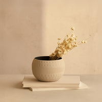 Textured grey metal bowl with dried stems on books for cozy modern home decor and sophisticated living room interior accents.