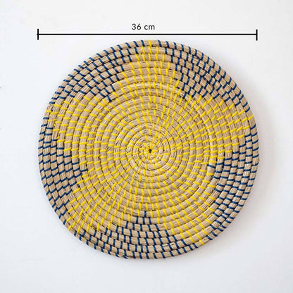 Handwoven seagrass round wall basket decor in yellow and charcoal with floral woven pattern and size guide on white.