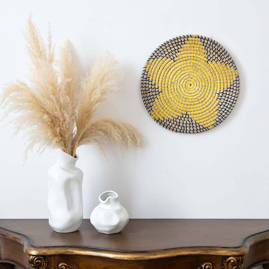 Handwoven seagrass wall basket decor in yellow and charcoal styled above a console table for boho home decoration.