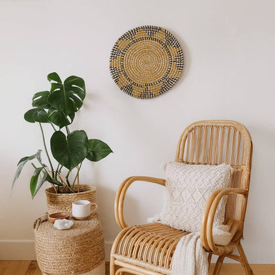Handwoven seagrass round wall basket decor in natural yellow and charcoal enhancing cozy living room wall styling.