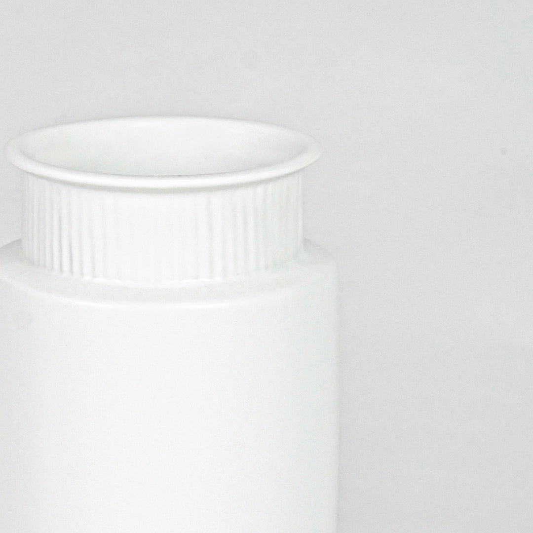 Closeup image of white ceramic ribbed vase for modern shelf decor styling with elegant matte finish display.