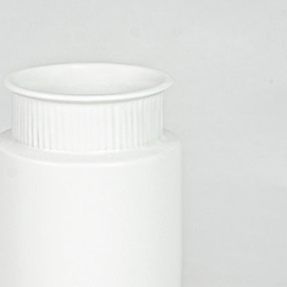 Closeup image of white ceramic ribbed vase for modern shelf decor styling with elegant matte finish display.