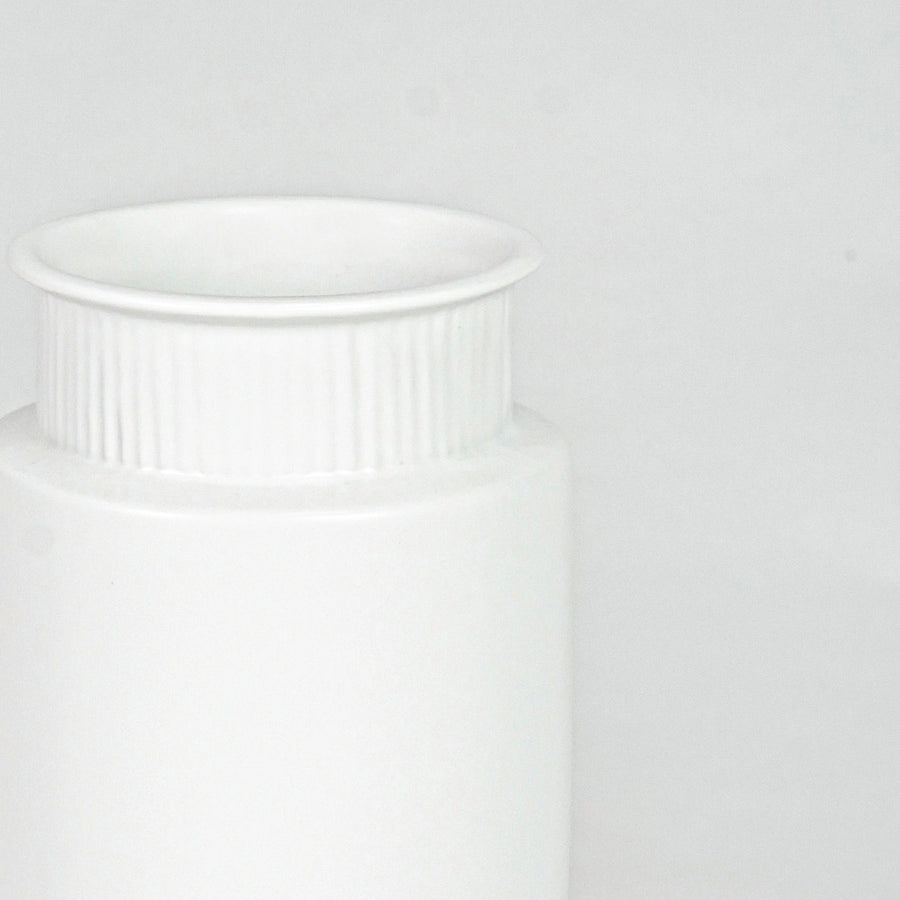 Closeup image of white ceramic ribbed vase for modern shelf decor styling with elegant matte finish display.