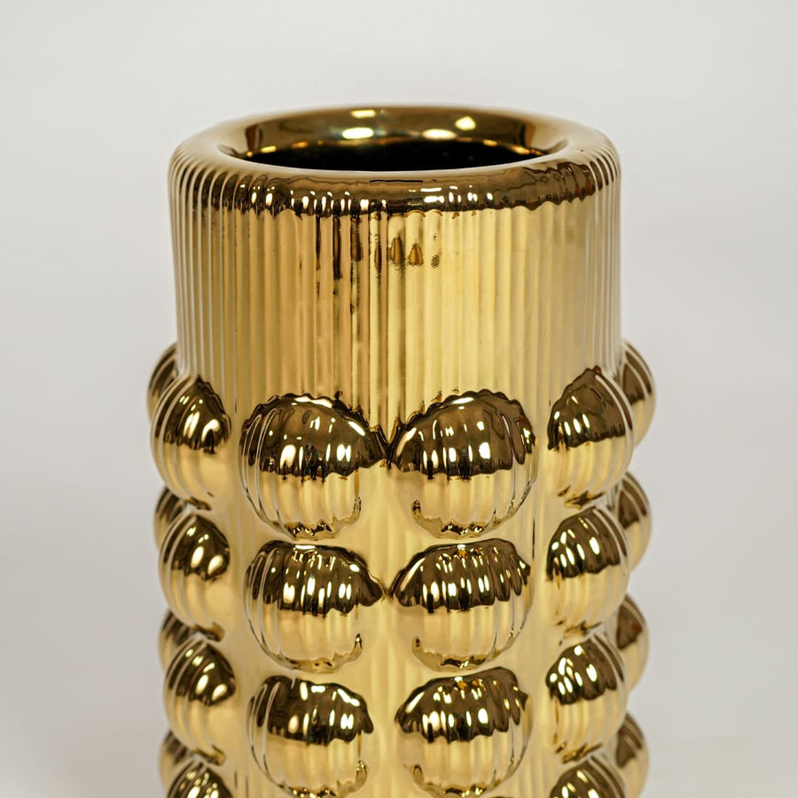 Closeup of gold finished metal vase with detailed skull motif showcasing bold artistic texture for home decor styling.