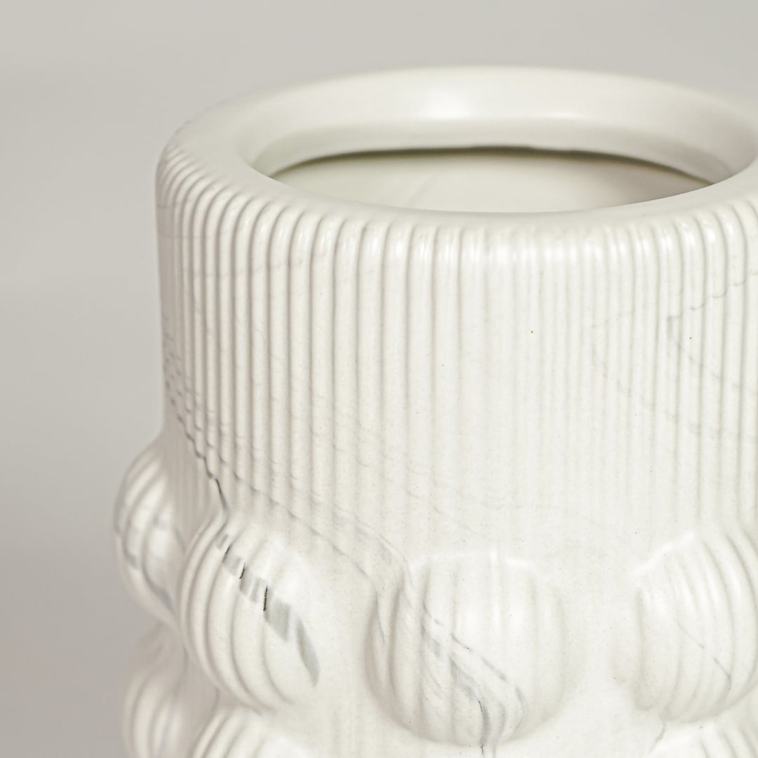 Closeup of matte white ceramic vase with embossed circular pattern ideal for elegant home decor shelf styling.