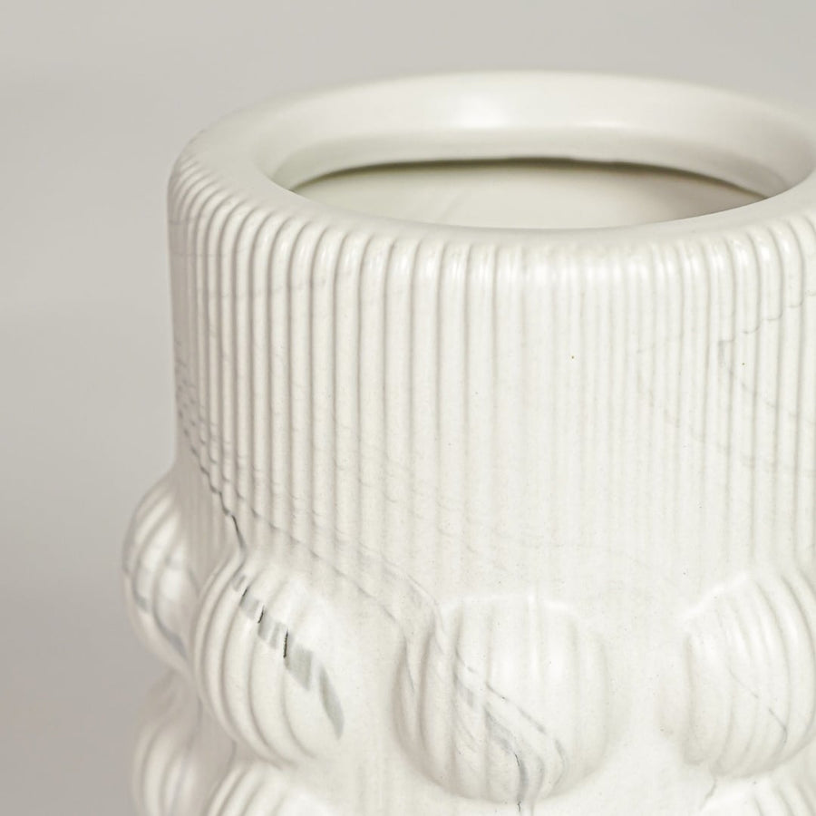 Closeup of matte white ceramic vase with embossed circular pattern ideal for elegant home decor shelf styling.