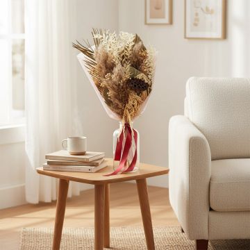 Dried floral bouquet arranged in vase on side table beside sofa adding cozy texture and soft natural charm to home Decor.