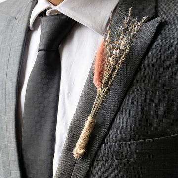 Elegant dried flower boutonniere with lavender stems pink preserved bloom and rustic jute wrap styled on black background decor.