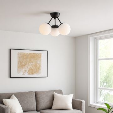 Modern ceiling light with three frosted glass globes on black frame glowing above sofa for stylish home interior lighting.