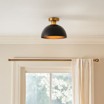 Modern black and gold ceiling light with dome shade glowing warmly above window for stylish home interior ceiling decor.