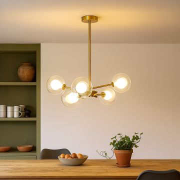 Gold molecular chandelier with spherical glass shades hanging in modern dining space creating stylish contemporary lighting.