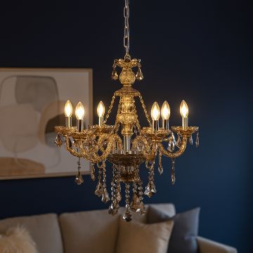 Golden chandelier with crystal droplets glowing warmly above sofa in modern living room interior design.