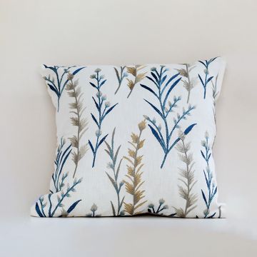 Botanical embroidered cushion in blue and gold tones displayed on a white background highlighting its detailed stitching and soft fabric texture.