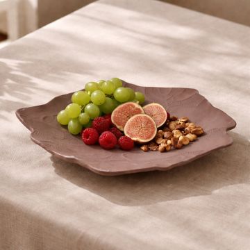Brown ceramic decorative platter placed on dining table adding rustic charm and artistic texture to modern home decor.