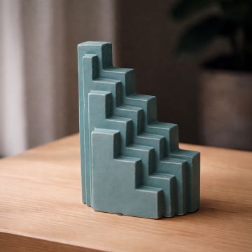 Teal ceramic stepped decorative sculpture styled on wooden console enhancing contemporary home decor setting.