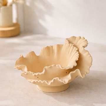 Beige ceramic ruffled decorative bowl placed on marble table adding warm and artistic charm to modern living room decor.