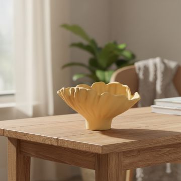 Yellow ceramic sculpted decorative bowl placed on wooden table adding vibrant modern touch to living room decor.