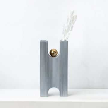 White dried leaf stems arranged in modern grey ceramic vase with gold accent elegant lifestyle home decor centerpiece.