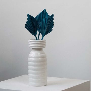 White ceramic vase styled with teal dried palm leaf stems for modern home decor accent.