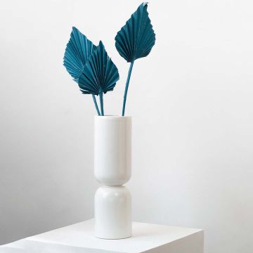 White ceramic vase styled with tall teal dried palm leaf stems for modern minimal home decor.