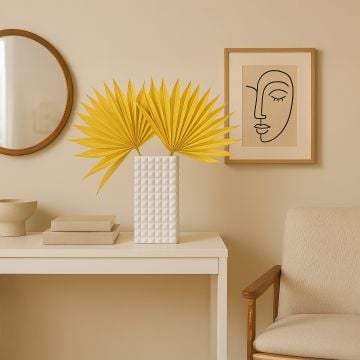 Yellow dried palm leaves in white textured vase styled on modern console table for living room home decor.