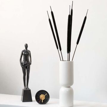 Elegant bulrush stems in a modern white vase styled with artistic decor adding natural charm to home interiors.