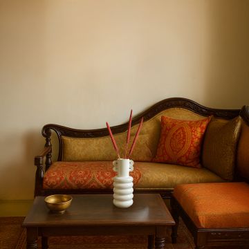 Elegant red millet stems in a modern white vase styled on a classic wooden sofa set for premium home decor.