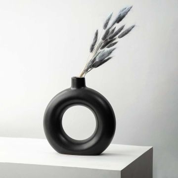Grey lagurus dried bunny tail grass styled in black ceramic vase lifestyle modern home decor on wooden table.