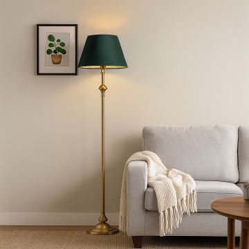 Golden metal floor lamp with dark green fabric shade styled in modern living room beside light grey sofa.
