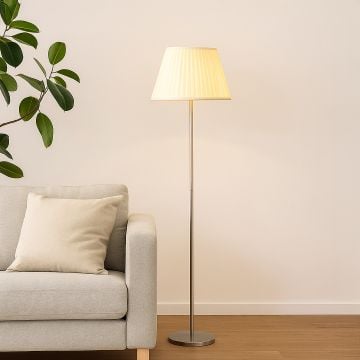 Elegant floor lamp with pleated fabric shade placed beside a modern grey sofa in a cozy living room.