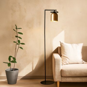 Contemporary black and gold floor lamp placed beside beige sofa in cozy living room setting with warm natural light.