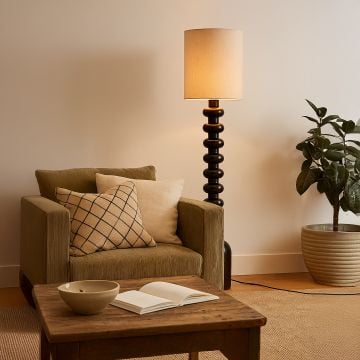 Modern dark wood floor lamp beside armchair in cozy living space styled with earthy decor and soft neutral tones.